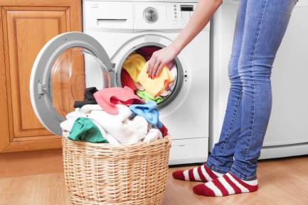En kvinna lägger tvätt i tvättmaskin