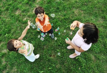 Tre barn som leker med blåsbubblor